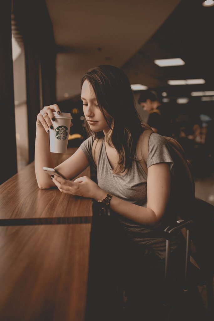 Girl looking at phone drinking coffee