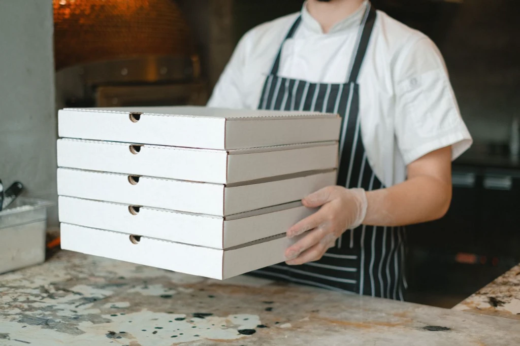 Worker giving pizzas to a customer